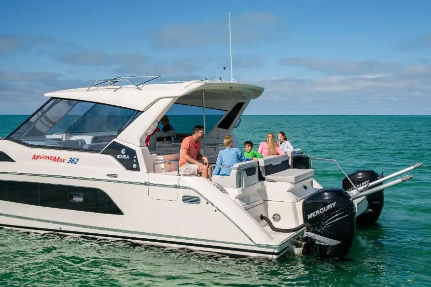 A group of five people relax on a MarineMax 362 boat, enjoying the calm, turquoise waters under a bright blue sky.
